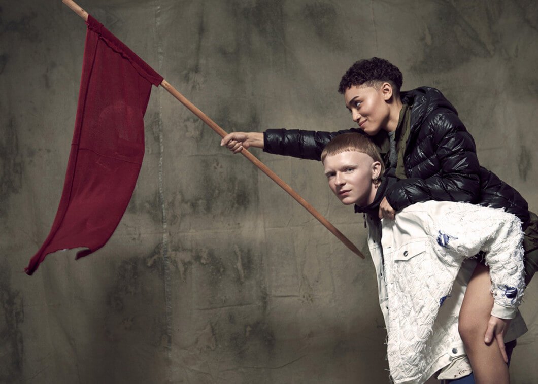 Zwei Menschen mit roter Flagge vor Wand auf der Fashion Revolution Week