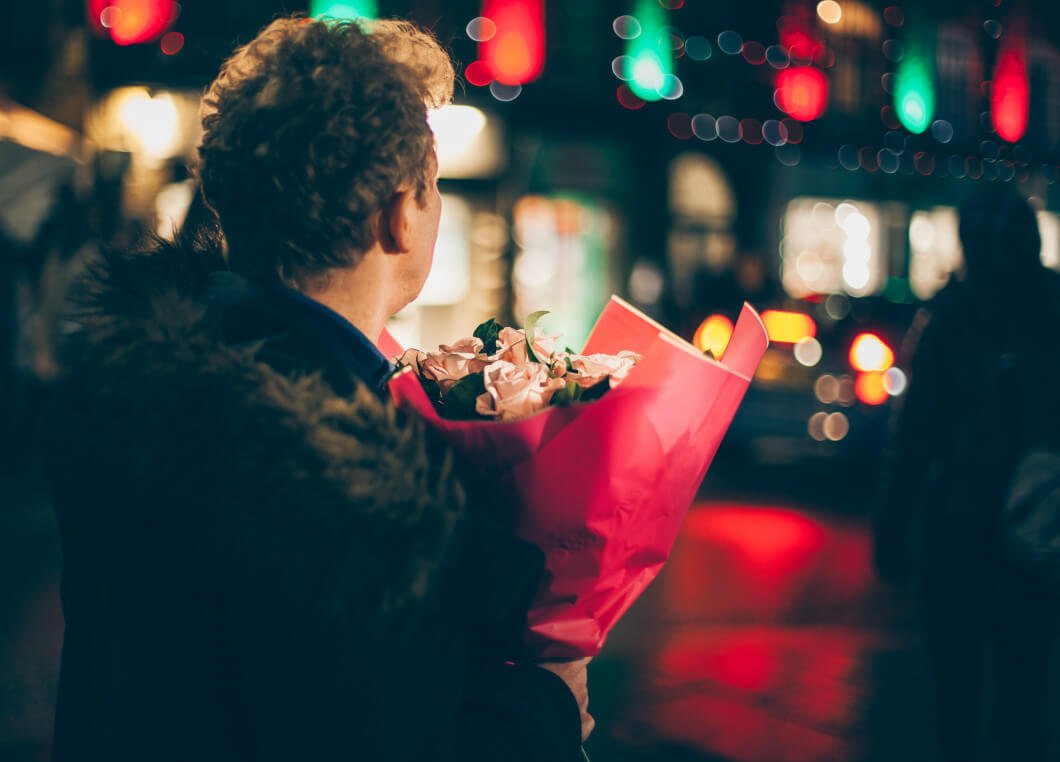 Mann mit Blumen in Abenddämmerung auf der Straße