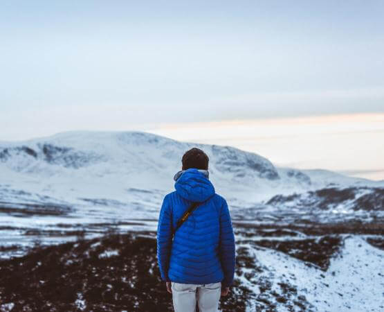 Frau in Daunenjacke in Winterlandschaft