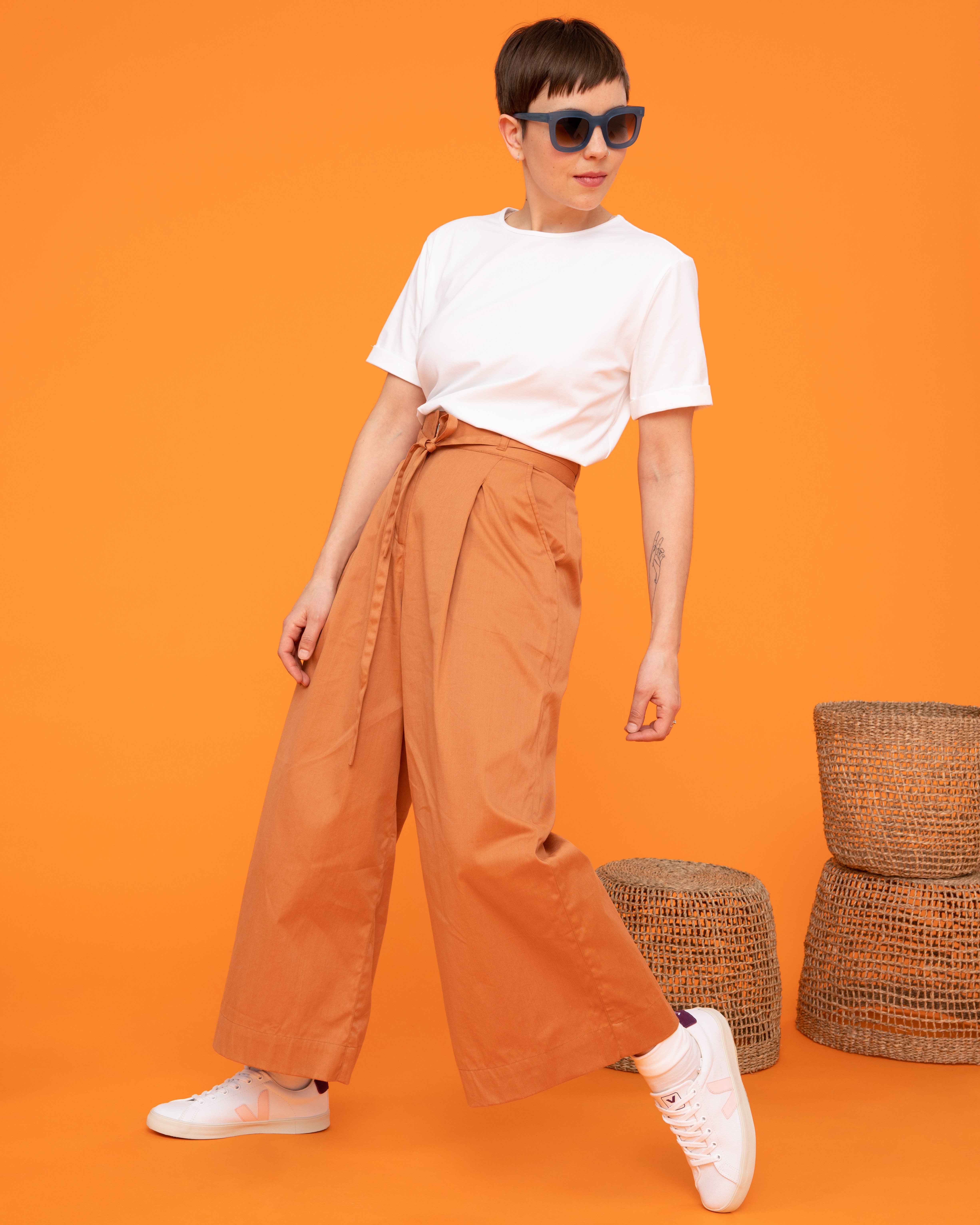 Frau trägt weißes Shirt und orangefarbene Hose