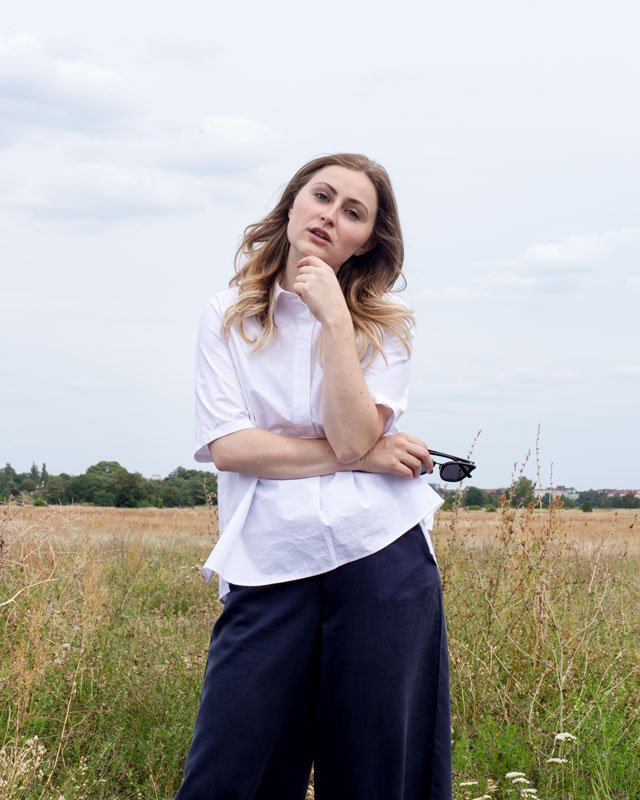 Frau in weißer Bluse und blauer Culottes vor Feld