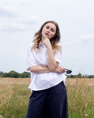 Frau in weißer Bluse und blauer Culottes vor Feld